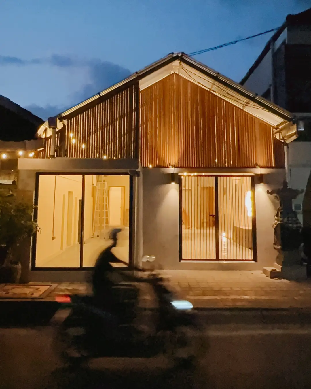 The Potato Bun Club restaurant in Amed, Bali at dusk, warm wooden facade and glowing windows